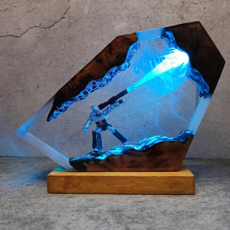 May include: A unique resin art piece featuring a robot figure with a weapon, set within a wooden and resin frame. The frame has a blue glowing effect, and the base is made of wood. The artwork is a decorative item.