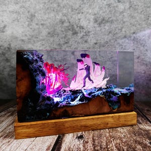 May include: A rectangular resin art piece with a wooden base. The artwork features a miniature figure running towards a glowing, abstract form. The resin is filled with colorful details, including purple, blue, and pink hues, and is set on a wooden base.
