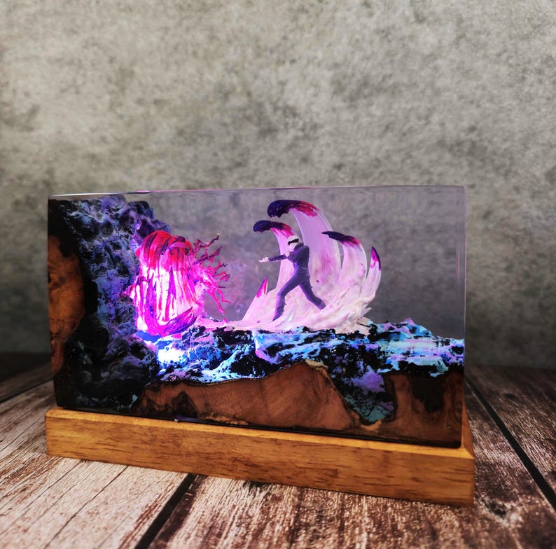 May include: A rectangular resin art piece featuring a miniature figure facing a glowing, abstract creature and wave-like forms. The artwork is set on a wooden base, with the scene illuminated by purple and blue lights, creating a fantasy theme.