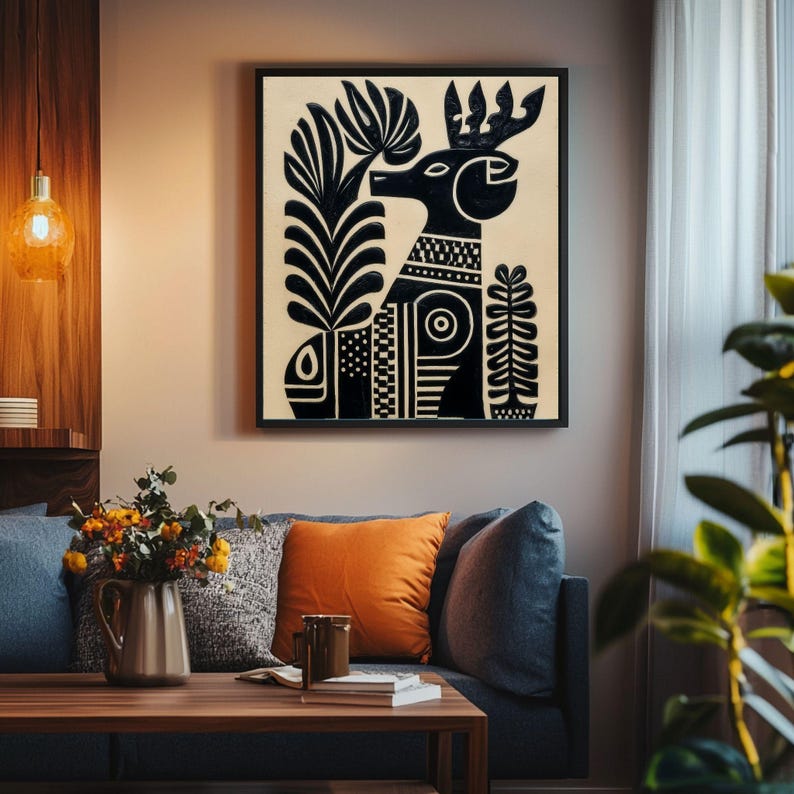 May include: Black and white art print of a stylized deer with geometric patterns and floral elements. The artwork is framed in a black square frame and hangs above a blue sofa with orange and gray pillows. The room has a modern, minimalist design.