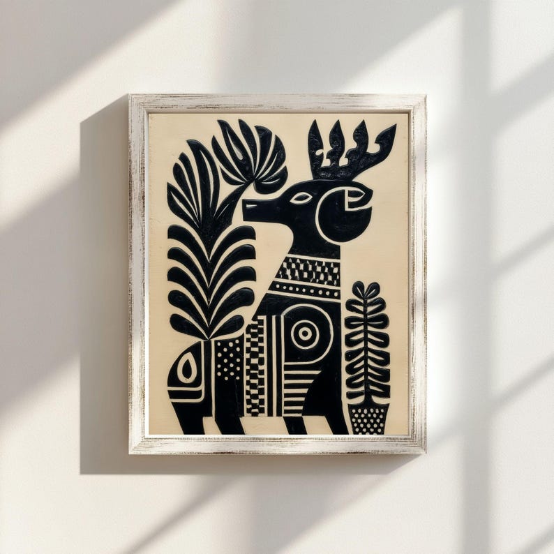 May include: Black and white framed art print featuring a stylized deer with intricate patterns and plant elements. The artwork has a folk art style, with a cream-colored background and a distressed white frame. The deer has a crown and is surrounded by stylized plants.