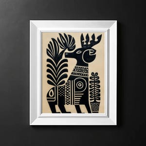 May include: A framed black and white folk art print featuring a stylized deer with elaborate patterns and plant motifs. The artwork is set against a beige background and framed in a white rectangular frame. The deer has a decorative collar and antlers.