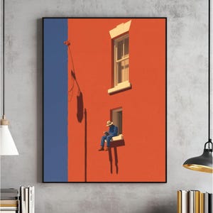 Op de afbeelding: Een ingelijste kunstdruk toont een persoon die in een raam leest. Het gebouw is fel oranje geschilderd met een blauwe verticale streep. De persoon draagt blauwe kleding en een hoed. Het kunstwerk heeft een minimalistische stijl.