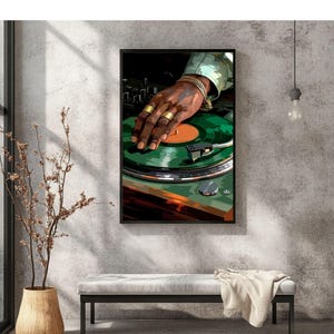 Pode incluir: Uma impress&atilde;o art&iacute;stica emoldurada retrata a m&atilde;o de um DJ com an&eacute;is e pulseiras douradas em um disco de vinil verde. A vitrola est&aacute; contra uma parede cinza texturizada, com um banco e um vaso decorativo em primeiro plano.