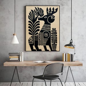 May include: Black and beige framed art print featuring a stylized deer with intricate patterns and floral elements. The artwork has a folk art style, with a black deer figure and plant designs on a beige background. The print is displayed on a wooden desk.