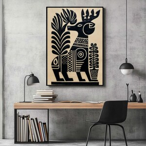 May include: Black and white art print featuring a stylized deer with large antlers and geometric patterns. The artwork includes plant-like elements on either side of the deer. The print is framed and displayed on a wall.