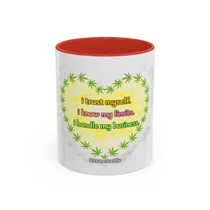 Puede incluir: Taza de cerámica blanca con interior rojo. La taza presenta un diseño en forma de corazón hecho de hojas de cannabis verdes, con el texto "i trust myself. i know my limits. i handle my business." El asa está en el lado derecho.
