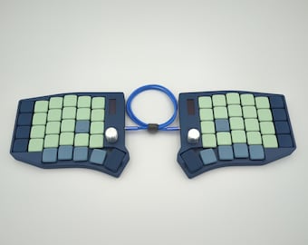 May include: A split ergonomic keyboard with a dark blue base, featuring light green and blue keycaps. The keyboard is connected by a blue cable and has silver knobs and small screens.