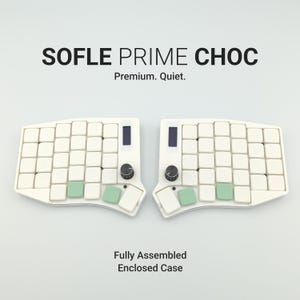 Könnte beinhalten: Eine geteilte, ergonomische Tastatur mit weißen Tastenkappen und grünen Akzenttasten. Die Tastatur hat zwei schwarze Knöpfe und zwei kleine Bildschirme. Der Text "SOFLE PRIME CHOC" und "Premium. Quiet." stehen oben. Der Text "Fully Assembled Enclosed Case" steht unten.