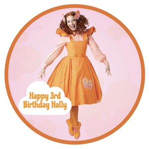 May include: A girl wearing a bright orange dress with a cloud-shaped banner that says "Happy 3rd Birthday Holly".
