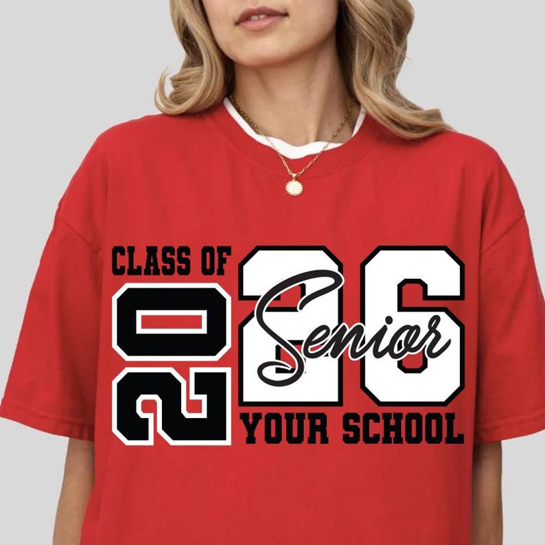 Pode incluir: Uma t-shirt vermelha com o texto "CLASS OF 26 Senior YOUR SCHOOL" em preto e branco. A t-shirt tem gola redonda e mangas curtas.