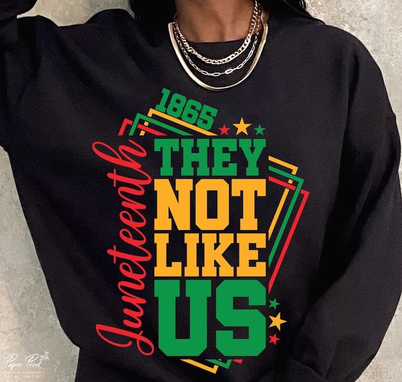 May include: Black sweatshirt with a graphic design featuring the text "Juneteenth" in red script, and the words "1865 THEY NOT LIKE US" in green and yellow. The design includes stars and geometric shapes.