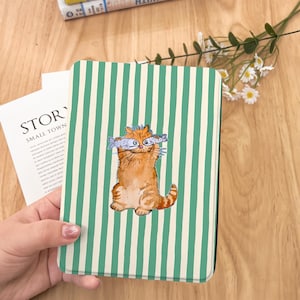May include: A green and white striped book cover with a cartoon illustration of a cat holding two fish in front of its eyes. The cat is orange and white and has a happy expression.