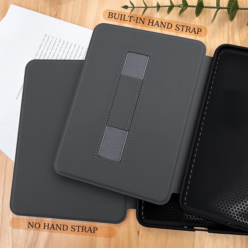 May include: A dark gray tablet case with a built-in hand strap and a stand. The case is open, revealing the interior and the text "BUILT-IN HAND STRAP" and "NO HAND STRAP". The case is designed to protect the tablet.