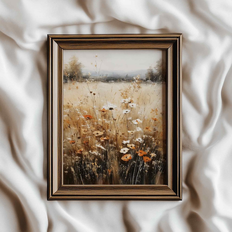 K&ouml;nnte beinhalten: Gerahmtes Gem&auml;lde eines Feldes mit Wildblumen in Beige-, Orange- und Wei&szlig;t&ouml;nen. Das Kunstwerk ist in einem braunen Holzrahmen gefasst. Das Gem&auml;lde zeigt eine ruhige Landschaft mit einer weichen, nat&uuml;rlichen &Auml;sthetik.