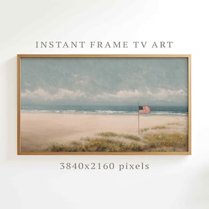 May include: A framed landscape painting of a beach scene with an American flag. The artwork features a sandy beach, ocean waves, and a cloudy sky. The frame is gold, and the text "INSTANT FRAME TV ART" is at the top.