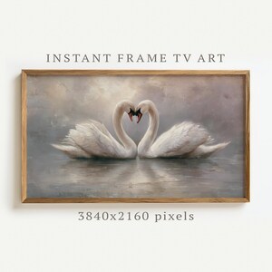 Puede incluir: Una obra de arte enmarcada que presenta dos cisnes blancos con sus cuellos formando un corazón. La pintura está ambientada sobre un fondo suave y apagado con el texto "INSTANT FRAME TV ART" y "3840x2160 píxeles". El marco es de madera.