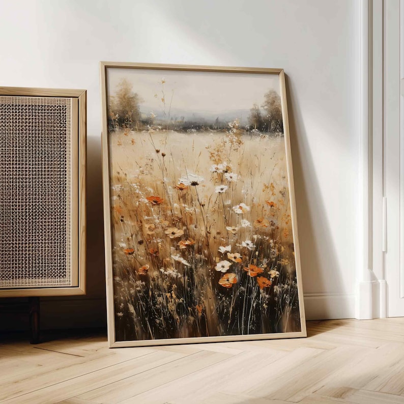 K&ouml;nnte beinhalten: Gerahmter Kunstdruck, der ein Feld mit Wildblumen in Orange, Wei&szlig; und Gelb zeigt. Das Kunstwerk zeigt hohes Gras und einen sanften, neutral get&ouml;nten Himmel. Der Rahmen ist helles Holz.