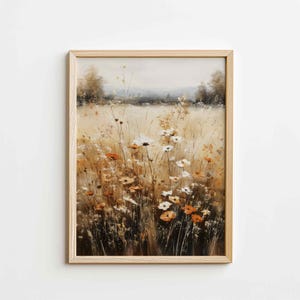 May include: A framed art print depicting a field of wildflowers in shades of orange, white, and brown. The artwork has a soft, painterly style, with a light brown wooden frame.