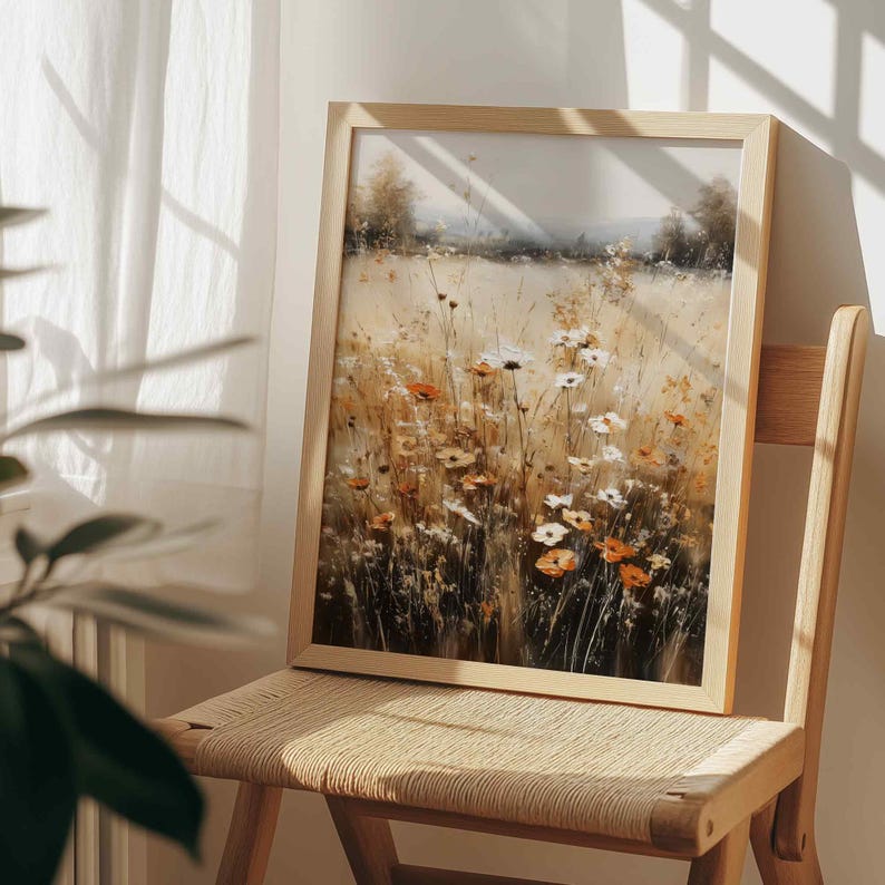 May include: A framed rectangular wall art print featuring an impressionistic painting of a sunlit meadow filled with tall grasses and wildflowers in shades of white, orange, and golden yellow, set within a light-toned wooden frame.