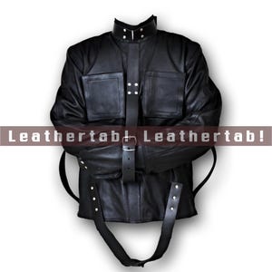 Könnte beinhalten: Schwarze Lederjacke mit hohem Kragen, zwei Vordertaschen und einem Gürtelverschluss. Die Jacke hat Riemen und Metallknopfdetails. Der Text "Leathertab! Leathertab!" ist auf dem Bild aufgedruckt.