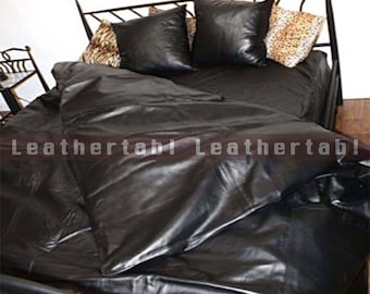 May include: A black leather bed set with a metal frame. The set includes a comforter, two square pillows, and two patterned pillows. The bedding is arranged on the bed, creating a luxurious and stylish look. The text "Leathertab! Leathertab!" is visible.