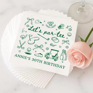 May include: White paper napkins with green golf-themed illustrations and text. The design includes golf clubs, a golf cart, and the phrase "Let's par-tee." The text "ANNIE'S 30TH BIRTHDAY" is also printed on the napkins.