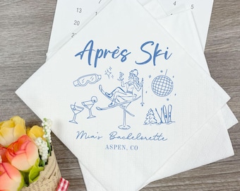 May include: White paper napkins with a blue illustration and text. The design includes ski goggles, cocktails, a disco ball, and a woman on skis. The text reads "Après Ski" and "Mia's Bachelorette, Aspen, CO."