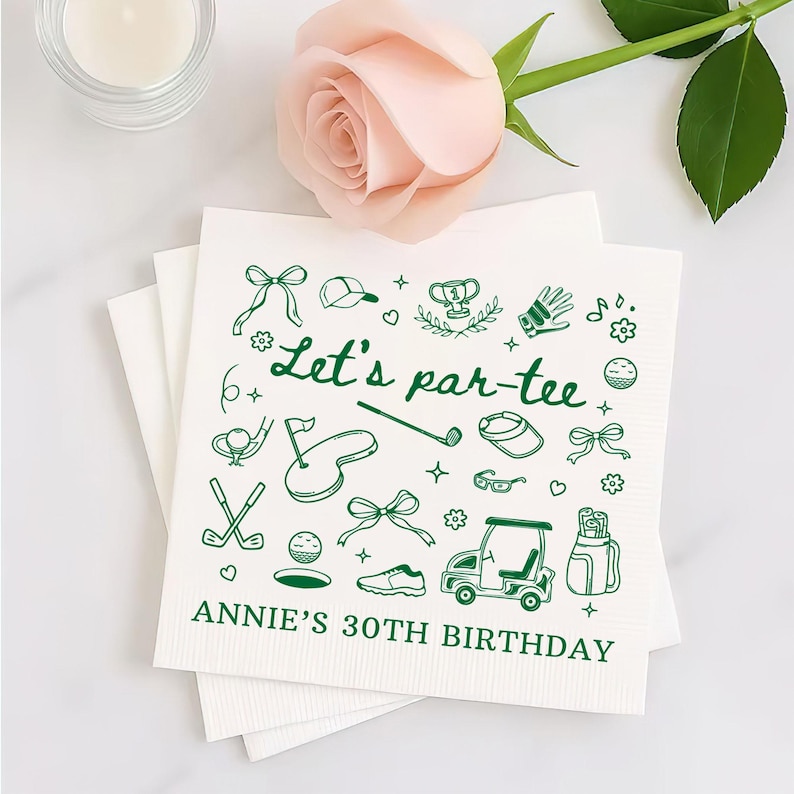 May include: White square paper napkins with green golf-themed doodles and the text "Let's par-tee" and "ANNIE'S 30TH BIRTHDAY". The napkins are stacked and decorated with a pink rose and a candle.
