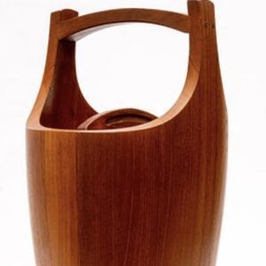 以下が含まれることがあります： ハンドル付きの木製アイスバケツ。バケツは暖色系の木材で作られており、上部に湾曲したハンドルが付いています。 デザインはシンプルでエレガントで、滑らかで磨かれた仕上がりです。 バケツはおそらく飲み物を冷やすために使用されます。