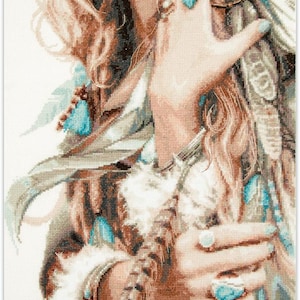 Pode incluir: Obra de arte em ponto cruz que retrata uma mulher com longos cabelos loiros ondulados, adornada com joias turquesas e penas. A obra apresenta pontos detalhados, mostrando um estilo boêmio com foco na textura e na cor.