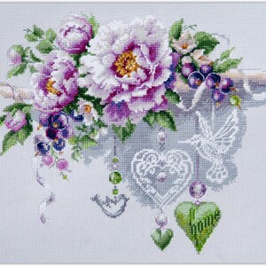 May include: Cross-stitch design featuring a floral arrangement of purple and white peonies, berries, and greenery. Decorative elements include a hummingbird, heart-shaped pendants, and the word "home" on a green heart. The design is on a light gray background.