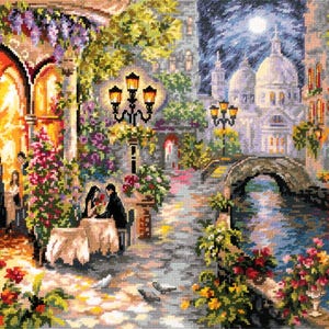 May include: A cross-stitch depiction of a romantic evening scene. A couple dines at a table, surrounded by flowers and street lamps. A bridge and buildings are in the background, with a full moon in the night sky.