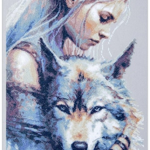 Può includere: Un modello a punto croce raffigurante una donna con lunghi capelli che abbraccia delicatamente un lupo. L'opera d'arte utilizza sfumature di blu, viola e beige, creando un effetto morbido e strutturato. Il volto della donna è rivolto verso il basso e gli occhi del lupo sono concentrati.