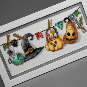 Può includere: Un ricamo a punto croce incorniciato con elementi a tema Halloween. Il design include un cappello da strega, una zucca, una bottiglia di pozione e un teschio, tutti collegati da gagliardetti colorati. L'opera d'arte è su sfondo bianco.