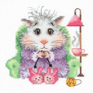 Könnte beinhalten: Kreuzstichbild einer Cartoon-Katze beim Stricken. Die Katze trägt einen lila Schal und rosa Hasenpantoffeln. Eine rosa Lampe und eine Teetasse sind im Hintergrund. Ein Knäuel gelber Wolle und Stricknadeln befinden sich in den Pfoten der Katze.