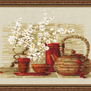 Op de afbeelding: Kruissteekkunstwerk van een stilleven met een theepot, kopjes en een bloeiende tak. De theepot en kopjes zijn roodbruin, met een geweven textuur. De achtergrond is een neutraal beige en de lijst is bruin.