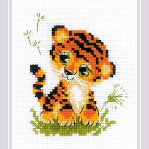 Può includere: Design a punto croce di un simpatico cucciolo di tigre con strisce arancioni e nere, seduto nell'erba verde. La tigre ha grandi occhi verdi e baffi bianchi. Fiori di tarassaco sullo sfondo. Il disegno è su tessuto bianco.
