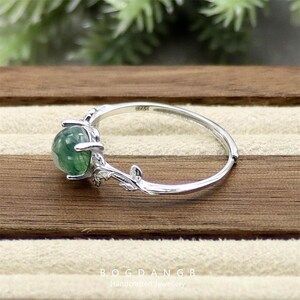 May include: A silver ring with a green agate gemstone and a delicate branch design. The ring is marked with "925" on the band.