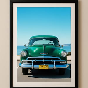 May include: Framed print of a classic green car with chrome detailing and a yellow number plate. The car is positioned against a backdrop of a blue sky and sea. The number plate displays "A55 886".