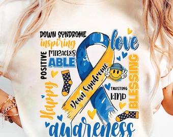 May include: Cream-colored t-shirt with a blue and yellow ribbon design promoting Down Syndrome awareness. The design includes the words "Down Syndrome," "awareness," "love," and other positive affirmations. Small hearts and socks are also featured.