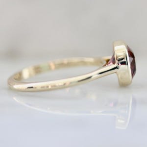 Hot Honey Pink-Peach Tourmaline Ring featuring a 1.81 carat cushion cut lab-created tourmaline set in 14k yellow gold. The gemstone glows with vibrant hues of pink, peach, orange, and red that shift in different lighting. A rounded bezel setting keeps the design sleek and modern, while the slim 1.71 mm band makes it perfect for stacking with other rings. A versatile and radiant gemstone ring that blends everyday luxury with a bold pop of color.