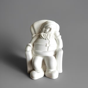 May include: A white Santa Claus figurine seated in a chair, with a full beard and a sack over his shoulder. The figure is detailed with a belt and boots, perfect for holiday decor.