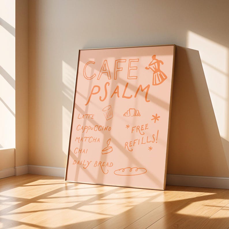 Puede incluir: Un p&oacute;ster enmarcado con las palabras "CAFE PSALM" en escritura naranja. El p&oacute;ster enumera bebidas de caf&eacute; y t&eacute;, y "FREE REFILLS!" tambi&eacute;n est&aacute; escrito en el p&oacute;ster. El p&oacute;ster est&aacute; apoyado contra una pared, con la luz del sol que atraviesa el suelo.