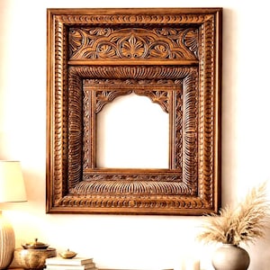 May include: A rectangular wooden mirror frame featuring intricate hand-carved floral and leaf motifs. The frame has a dark brown finish with a central arched opening and layered decorative borders that create a deep, textured appearance.
