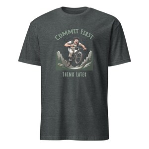 May include: A dark heather grey t-shirt with a graphic of a person riding a mountain bike downhill. The text "Commit First Think Later" is printed on the shirt.