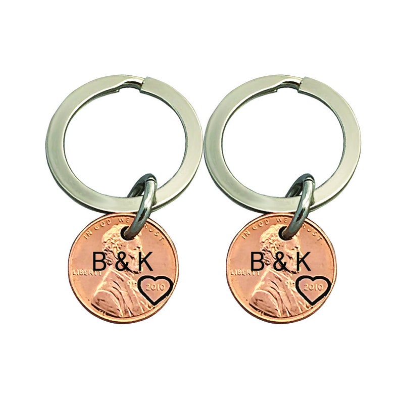 May include: Two silver keychains with copper penny charms. Each charm has the initials "B&K" and a small heart engraved on the front.