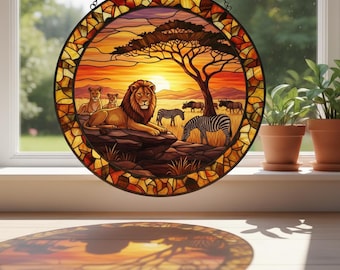 May include: Round stained glass window art depicting an African savanna scene. A lion and lionesses rest near a tree, with zebras and other animals in the background. The sunset sky is orange and yellow.