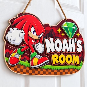 May include: A decorative wooden wall sign featuring the character Knuckles from Sonic the Hedgehog, a green Chaos Emerald, and the text NOAH'S ROOM in white and yellow letters. The sign has a brown rope hanger and a red, green, and brown background.
