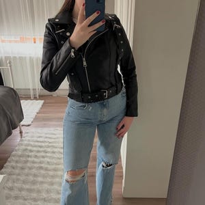 Arched Black Leather Biker Jacket for Women With Belted Waist And Zipper Detail – Trendy Moto Style Outerwear for Casual Looks Slim-Fit